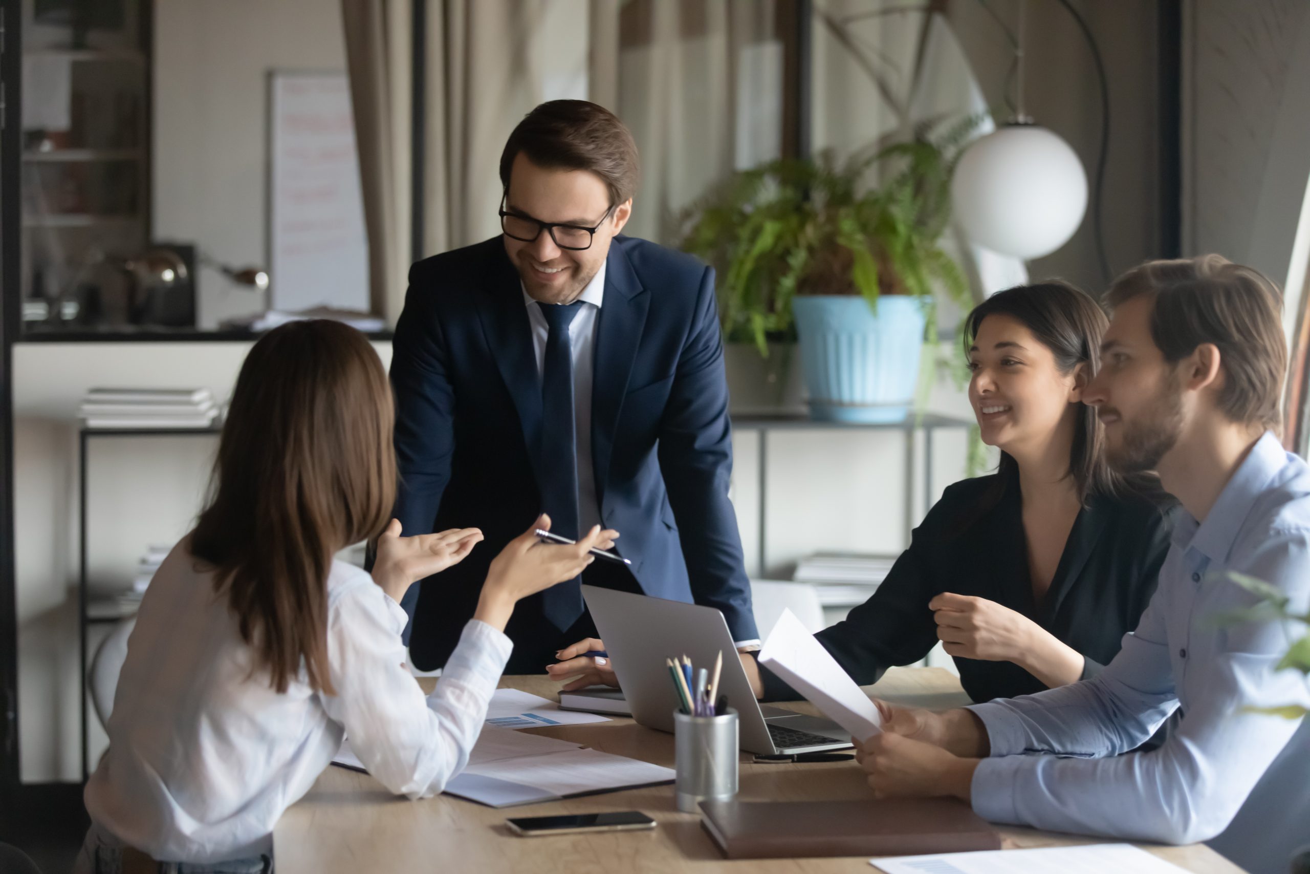 Smiling Team Leader With Employee Listening To Businesswoman At Corporate
